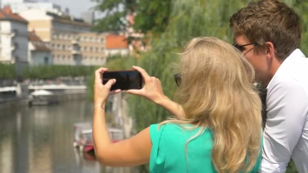 Tanımlanamayan sarışın kadın akıllı telefonuyla nehrin fotoğraflarını çekiyor. — Stok video