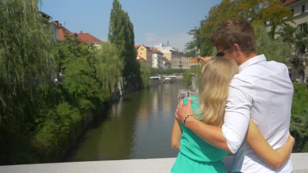 SLOW MOTION: Αγκαλιασμένο τουριστικό ζευγάρι απολαμβάνει τα γραφικά αξιοθέατα της Λιουμπλιάνα. — Αρχείο Βίντεο