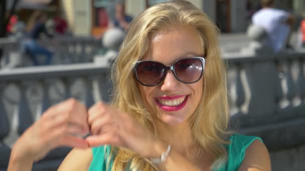 CHIUDI: Una donna caucasica sorridente crea la forma del cuore con le mani e le dita — Video Stock