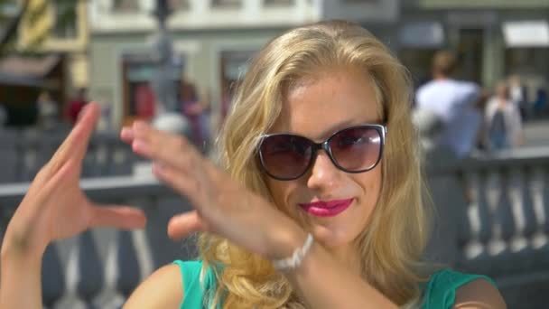 HANDHELD: Ragazza felice ride e fa un simbolo del cuore durante un viaggio turistico — Video Stock