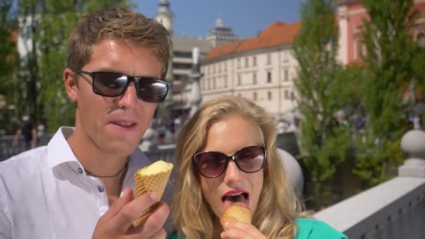 PORTRAIT: Vidám utazó pár eszik jégkrémet, miközben felfedezi Ljubljana. — Stock videók