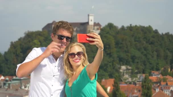 CLOSE UP: Happy man kisses his girlfriend on the cheek while taking selfies. — Stock Video
