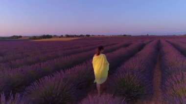 Sarı elbiseli neşeli kadın boş lavanta tarlasında yürüyor..