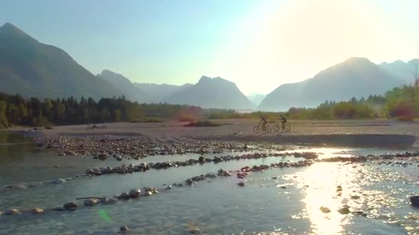 DRONE: Two guys on cross country bicycle ride cruise along the Soca river. — Stock Video