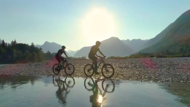 AERIAL: Dois amigos andando de bicicleta ao longo do rio Soca em um belo dia de verão. — Vídeo de Stock