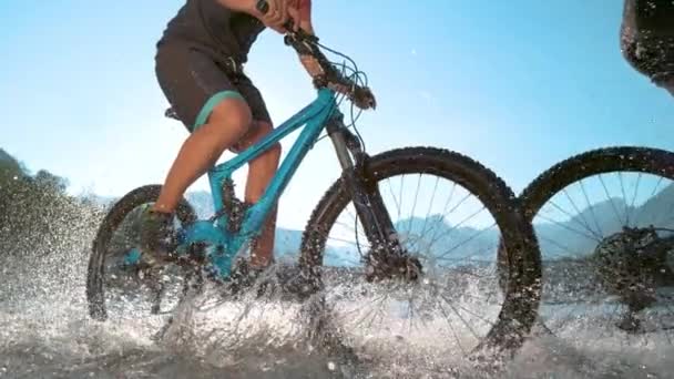 NIEDERES ENGEL: Unerkennbare Männchen sprühen beim Fahrradfahren Wasser in die Kamera. — Stockvideo