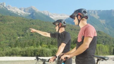 Dağ bisikleti süren iki arkadaş etrafa bakar ve manzarayı gösterir..