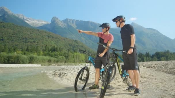 SLOW MOTION: Bikers discussing where to ride next while standing next to stream. — Stock Video