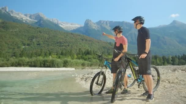 Медленное движение: Велосипедисты стоят у ручья и смотрят на природу . — стоковое видео