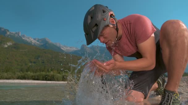 CERRAR: Guy ciclismo de montaña en Eslovenia salpica agua refrescante en su cara. — Vídeo de stock