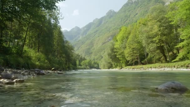 Klidná řeka Soca pomalu protéká kolem bujných zelených lesů pod horami — Stock video