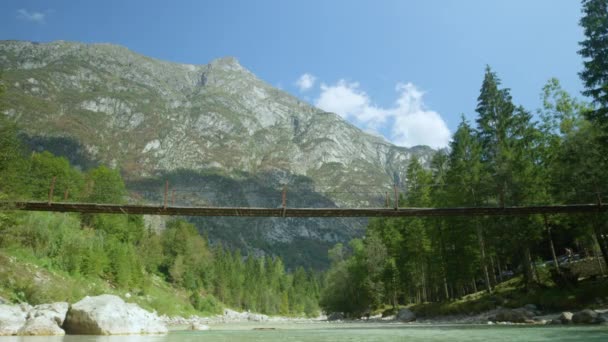 BAS ANGLE : Pont suspendu traverse le ruisseau verdoyant tranquille dans la vallée verte. — Video