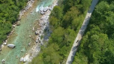 Güneşli bir günde, üç yolcu zümrüt Soca nehri boyunca bisiklet sürüyor..