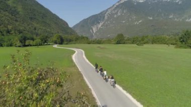 Bir grup turist, manzaralı vadideki boş yolda bisiklet sürüyor..