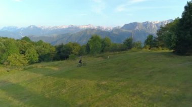 Erkek turist resimli yeşil dağlarda bisiklet sürerken eğleniyor..