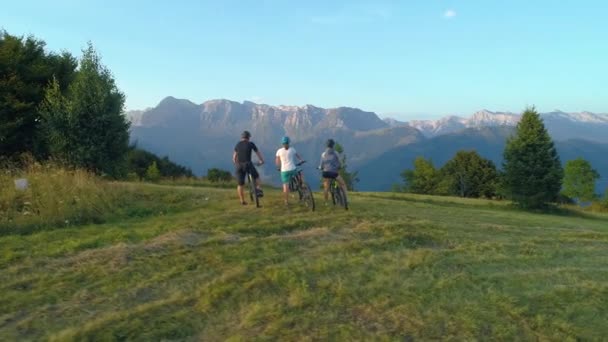 DRONE: Drie mountainbikers stoppen en observeren het pittoreske ochtendlandschap. — Stockvideo