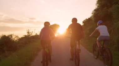 Tanınmayan bisikletçiler altın gün batımında boş yolda pedal çeviriyor..