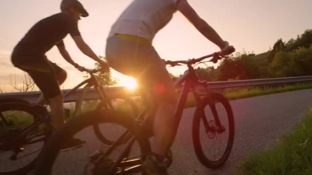 CLOSE UP: Radlergruppe fährt bei Sonnenuntergang mit E-Bikes über die leere Landstraße. — Stockvideo