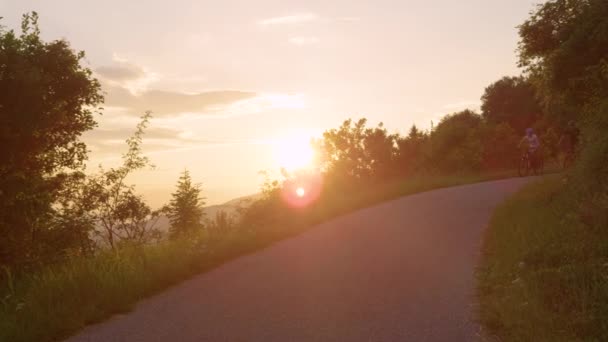SUN FLARE: троє туристів спускаються сонячною дорогою на ідилічний літній вечір — стокове відео