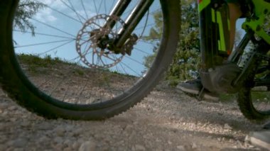 Tanınmaz haldeki bisikletçi çakıl yolda hız yaparken fren yapıyor.