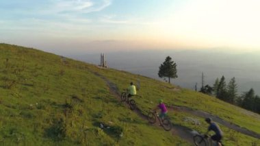 Aktif bir arkadaş grubu dağ bisikletlerini manzaralı bir patikada pedal çeviriyor.