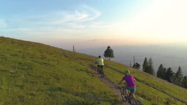 AERIAL: Malownicze ujęcie przyjaciół jeżdżących na rowerach górskich pod górę w słoneczny poranek. — Wideo stockowe