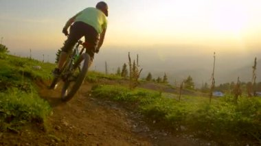 Altın güneş ışınları bisiklet süren turistlerin üzerinde bir patika boyunca parlıyor.