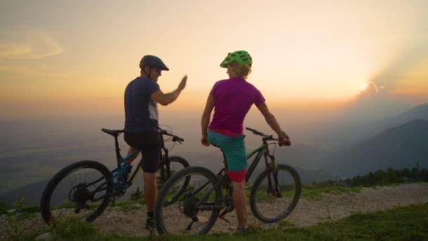SLOW MOTION: Veselí přátelé plácnutí při západu slunce po úspěšné jízdě na kole. — Stock video