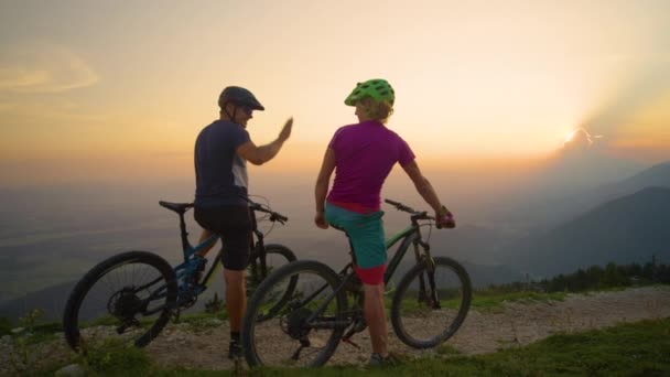 MOCIÓN LENTA: Alegre amigos de alta cinco al atardecer después de un exitoso paseo en bicicleta . — Vídeos de Stock