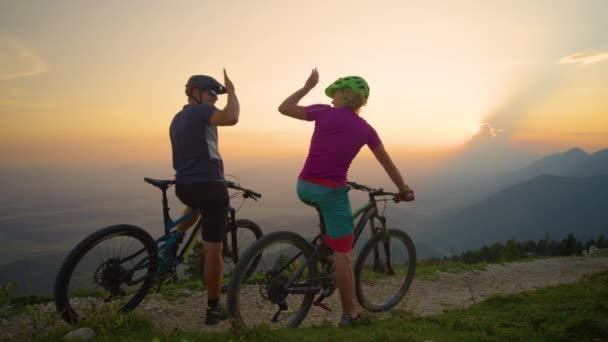 SLOW MotION: Радісні молоді велосипедисти п'ять на заході сонця, сидячи на велосипедах . — стокове відео