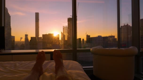 POV: tumbado en la cama y viendo el amanecer detrás de los modernos rascacielos. — Vídeos de Stock
