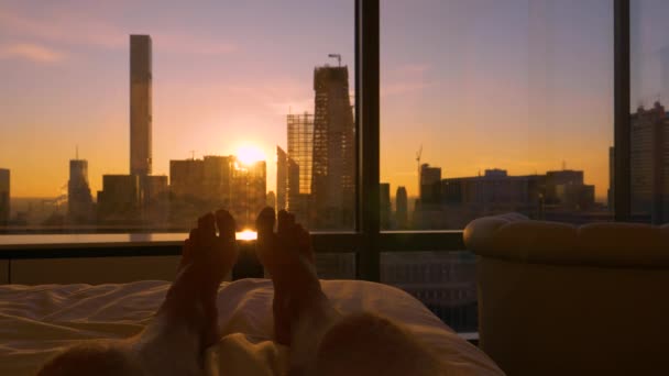 POV: 침대에 누워서 현대식 마천루 뒤에서 해 가 뜨는 것을 바라보는 모습. — 비디오