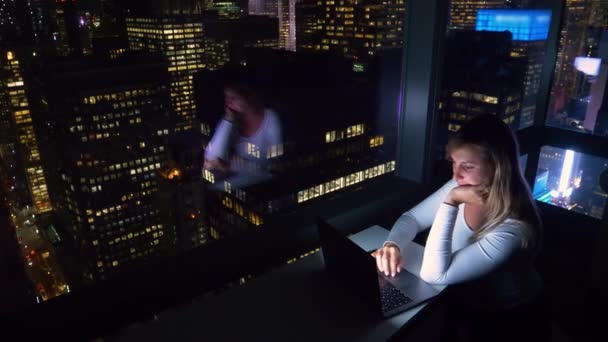 FECHAR UP: Estudante trabalhando até tarde da noite olha para os arranha-céus escuros. — Vídeo de Stock