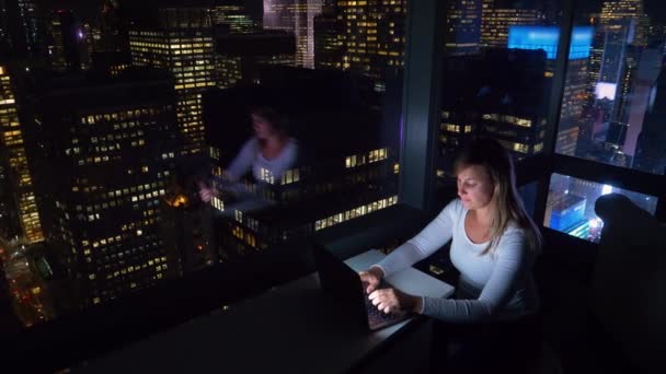 Žena sedí ve svém hotelovém pokoji nad Times Square a pracuje na notebooku