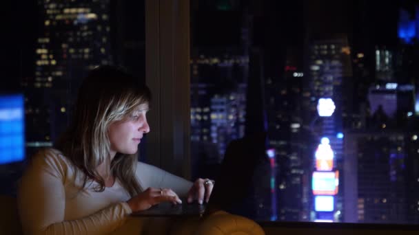 ZAMKNIJ DOF: Jasne światła Times Square flash poniżej dziewczyna pracuje na komputerze — Wideo stockowe