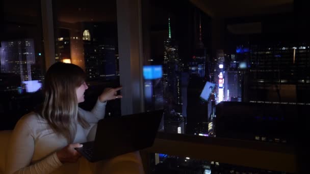 Vrouw filmt een vlog 's nachts vanuit haar hotelkamer met uitzicht op New York. — Stockvideo