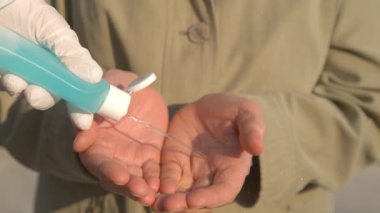 Cerrahi eldiven giyen kişi ellerini dezenfektanla yıkar.