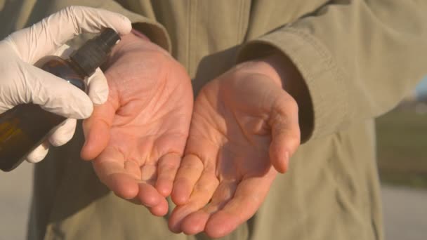 CLOSE UP: руки людини розбризкуються за допомогою дезінфікуючого засобу для рук під час пандемії COVID-19 — стокове відео