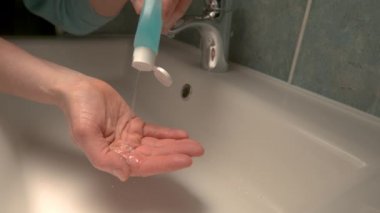 Tanınmayan kişi ellerini alkol el dezenfektanı ile yıkıyor.