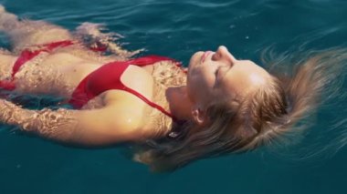 Tatilden zevk alan kız yaz sıcağından serinlemek için denizde yüzüyor.