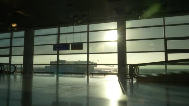 SILHOUETTE: Nierozpoznawalni turyści spieszą się z terminalu lotniskowego o świcie. — Wideo stockowe