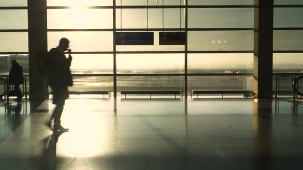 SilHOUETTE：金色的阳光照耀着穿过机场候机楼的通勤者. — 图库视频影像