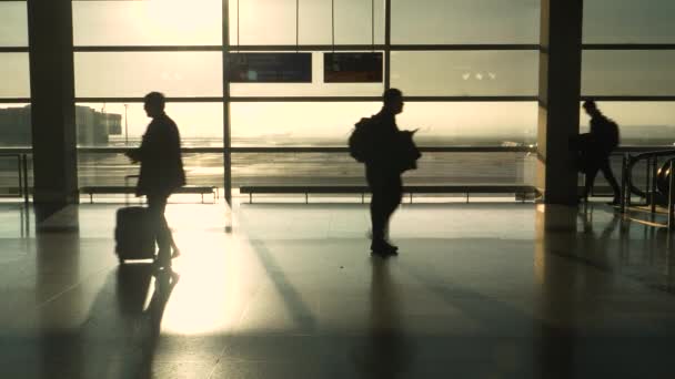 SILHOUETTE: Malownicze ujęcie tętniącego życiem terminalu na lotnisku w słoneczny poranek. — Wideo stockowe