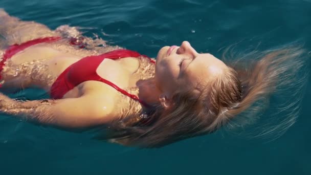 CLOSE UP: Girl enjoying her vacation floats in sea to cool off from summer heat Video Clip