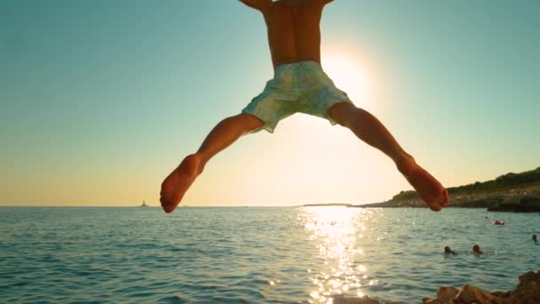 LENS FLARE: Golden sunbeams shine on excited man diving into the tranquil ocean. — Stock Video