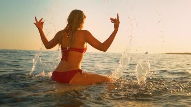 FECHAR UP: Mulher irreconhecível na prancha de surf brinca com a água do oceano ao pôr do sol — Vídeo de Stock