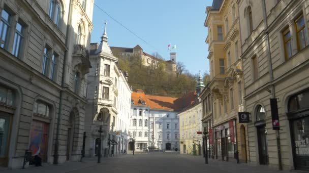 Turistgatan i Ljubljana gamla stan går tom under ett vackert slott på kullen — Stockvideo