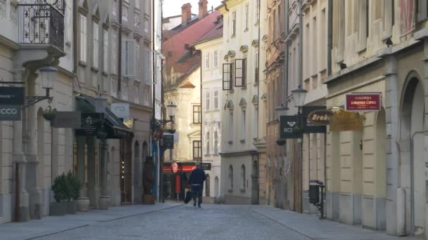 Onherkenbare locals lopen door lege straat in de oude stad van Ljubljana. — Stockvideo