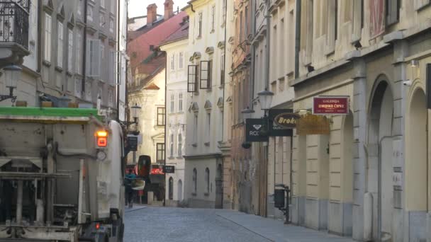 Nákladní automobil pro nakládání s odpady jede po prázdné ulici v centru Lublaně. — Stock video