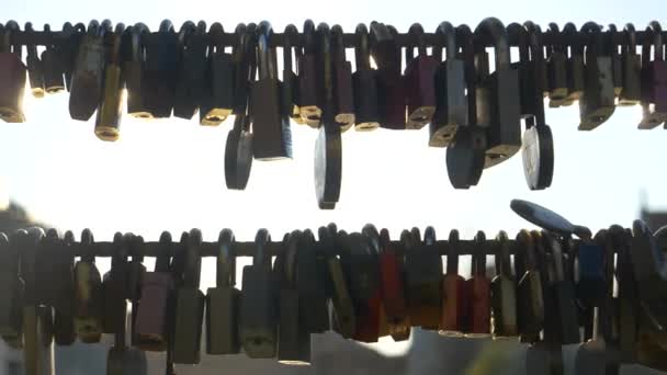 CLOSE UP: Otaliga metalllås och medaljonger hänger i trådar på en turist bro. — Stockvideo